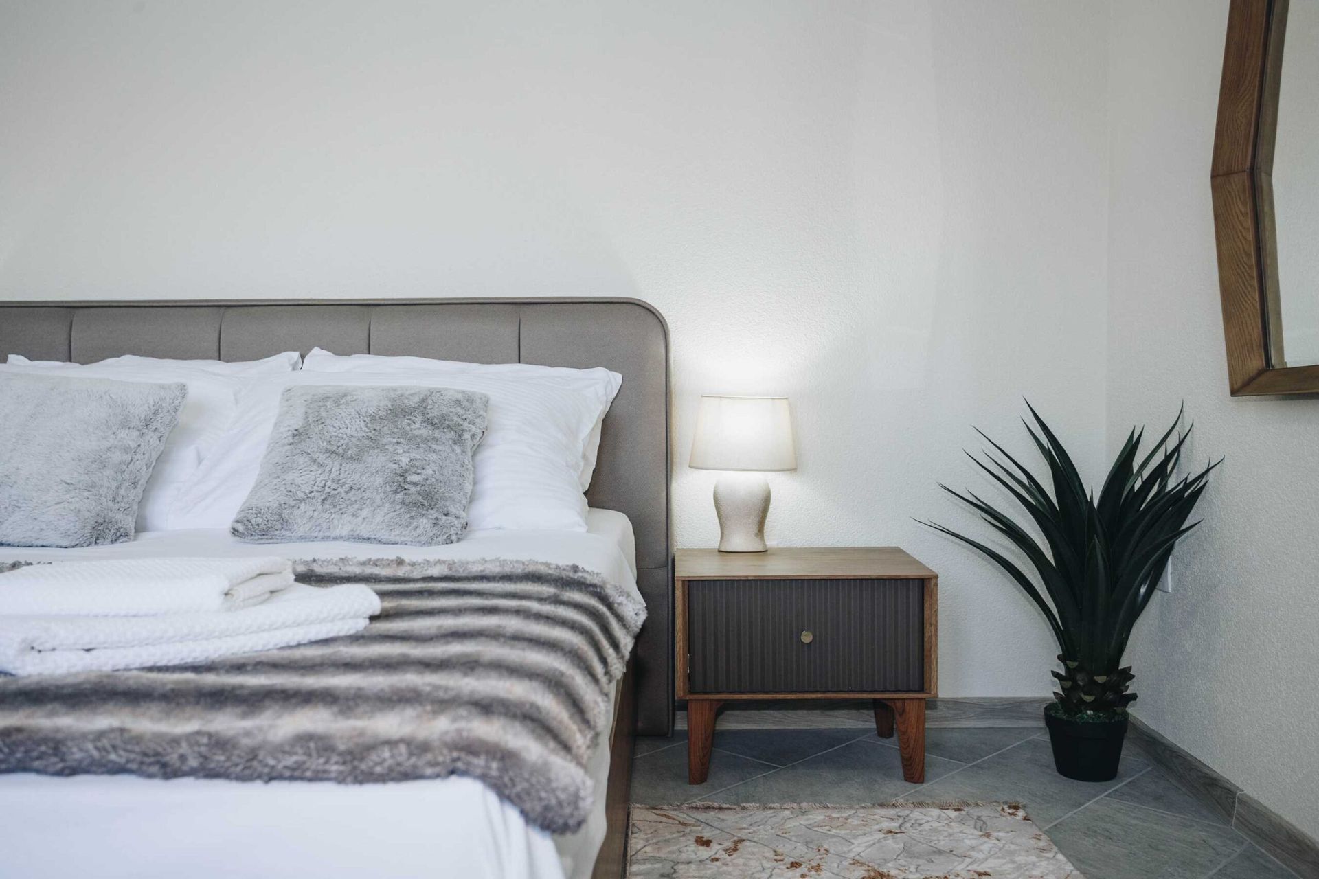 Cozy bedroom in a villa in Krašići, Montenegro: a double bed, a stylish nightstand, a lamp, and decor in the interior.