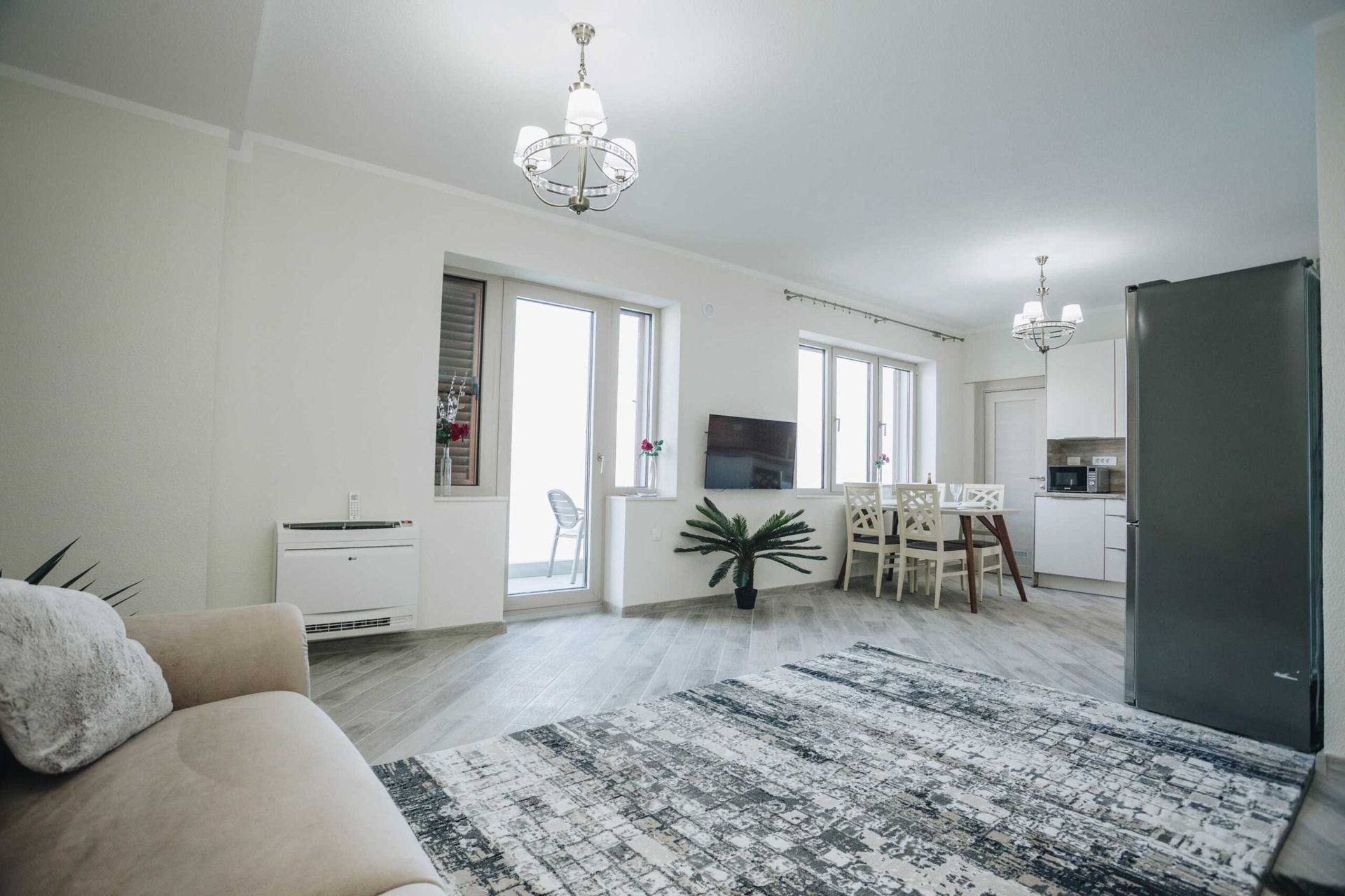 Bright living room with kitchen in a villa in Krašići, Montenegro: modern furniture, rug, access to the terrace, and sea view.