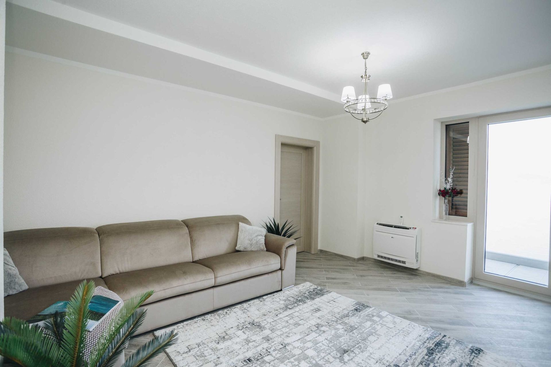 Bright living room with a beige sofa, rug, and access to the terrace in a villa in Krašići, Montenegro.