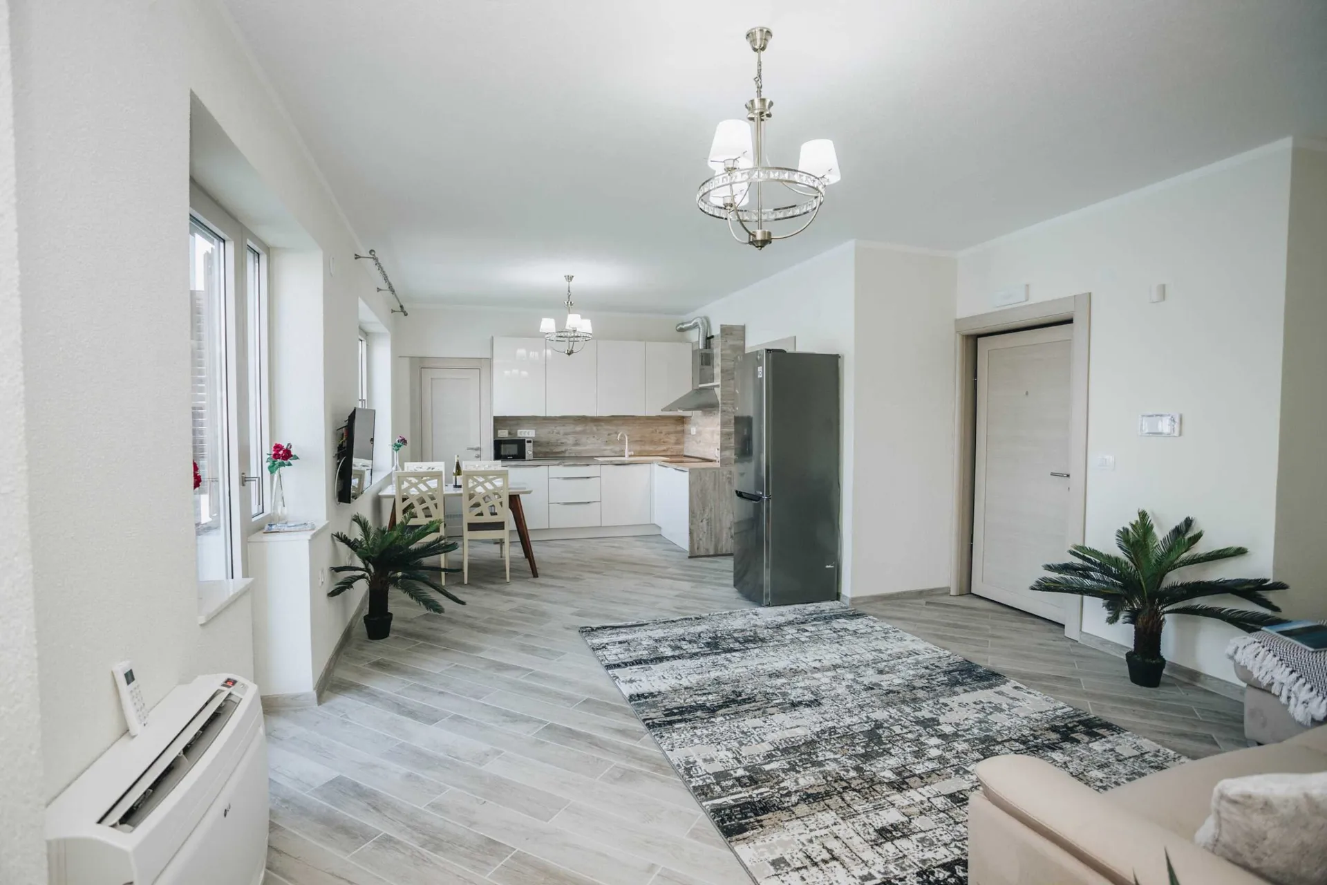 Open plan space featuring a kitchen, dining area with chairs, and a sofa on light wood flooring.