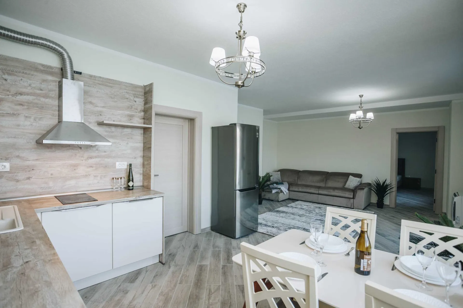 Open plan space showing a kitchen area, dining table with chairs, and a living room sofa.