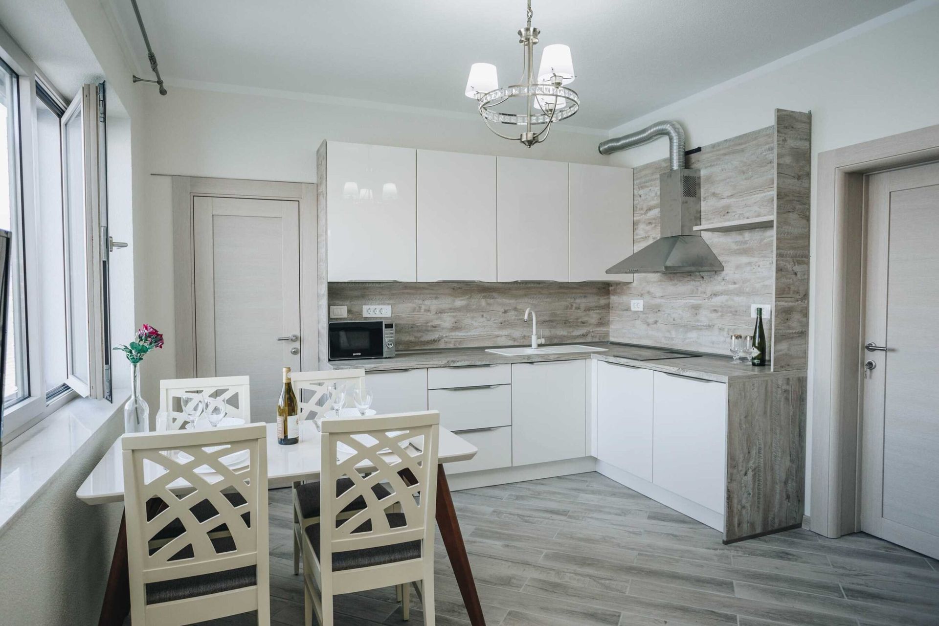 Modern kitchen with a white cabinet set and dining area in a villa in Krašići, Montenegro. Bright-toned interior.