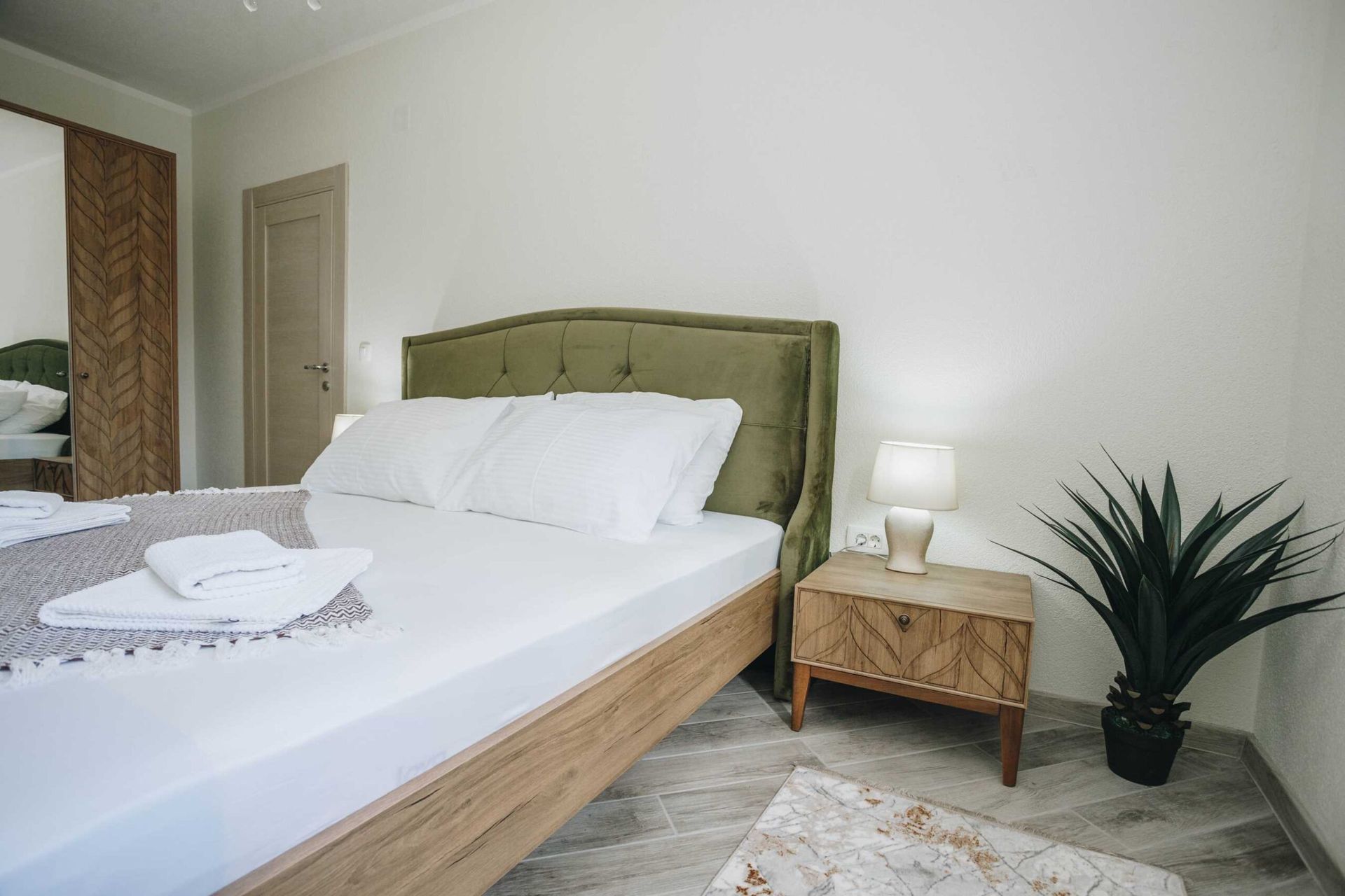 Bedroom with a double bed, green headboard, and wooden nightstand in a villa in Krašići, Montenegro.