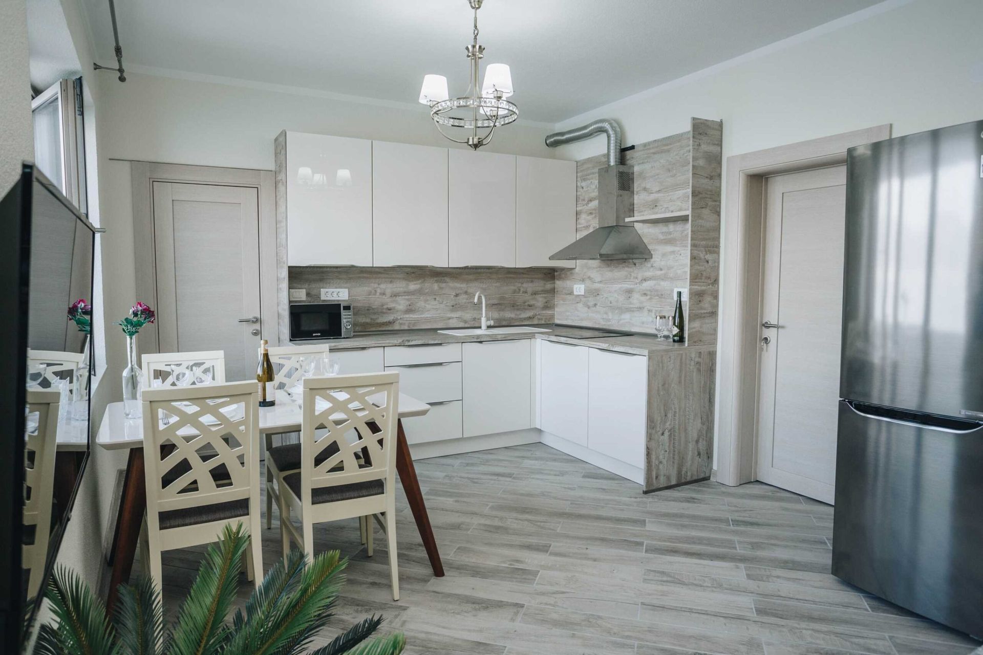 Modern kitchen with white cabinetry in a villa in Krašići, Montenegro: dining area, built-in appliances, and stylish decor.