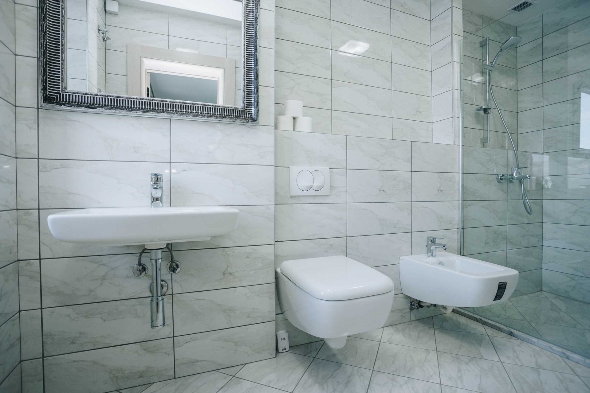 Modern bathroom with shower cabin and bidet in a villa in Krašići, Montenegro: marble-look tile finish.