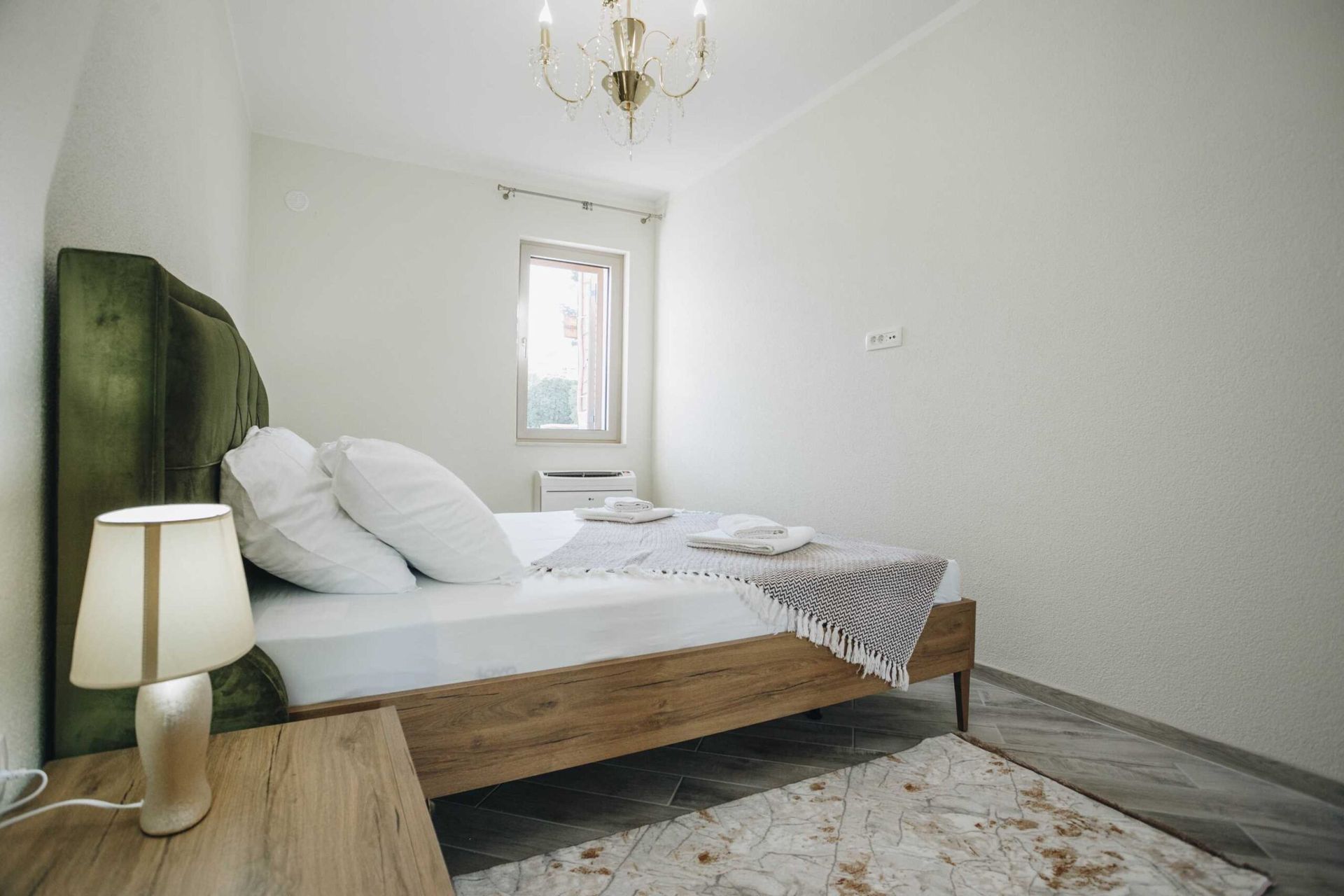 Cozy bedroom with a double bed and a green headboard in a villa in Krašići, Montenegro: interior with a chandelier.