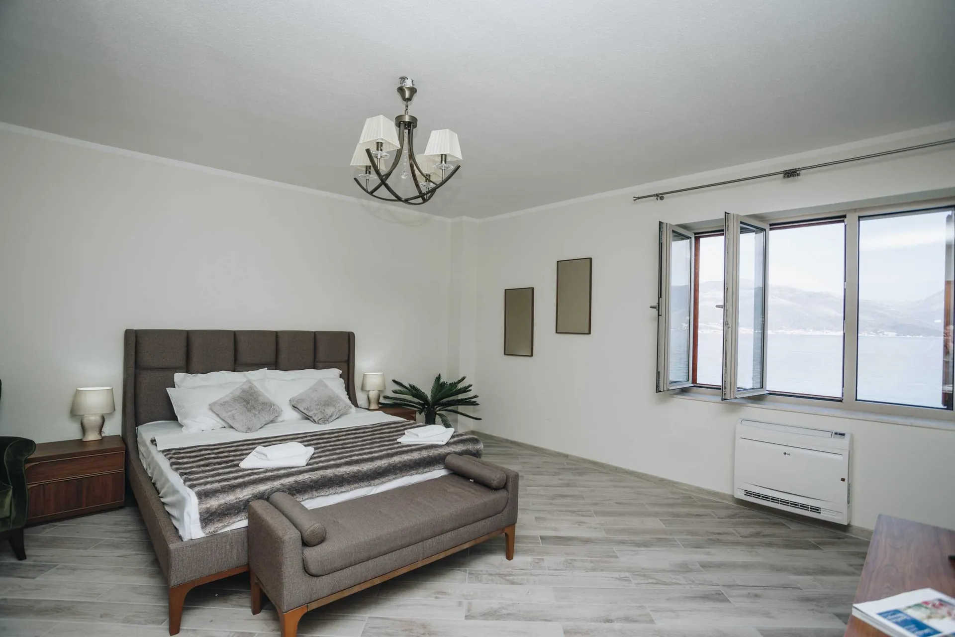 Bedroom featuring a large bed, nightstands, chandelier, and a window with a water view.