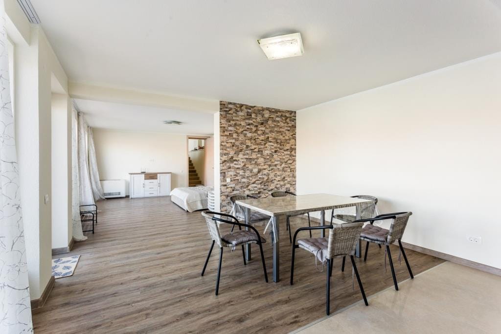 Living room with dining area in a villa in Krašići, Montenegro: stone finishes, light-colored furniture, and panoramic windows.