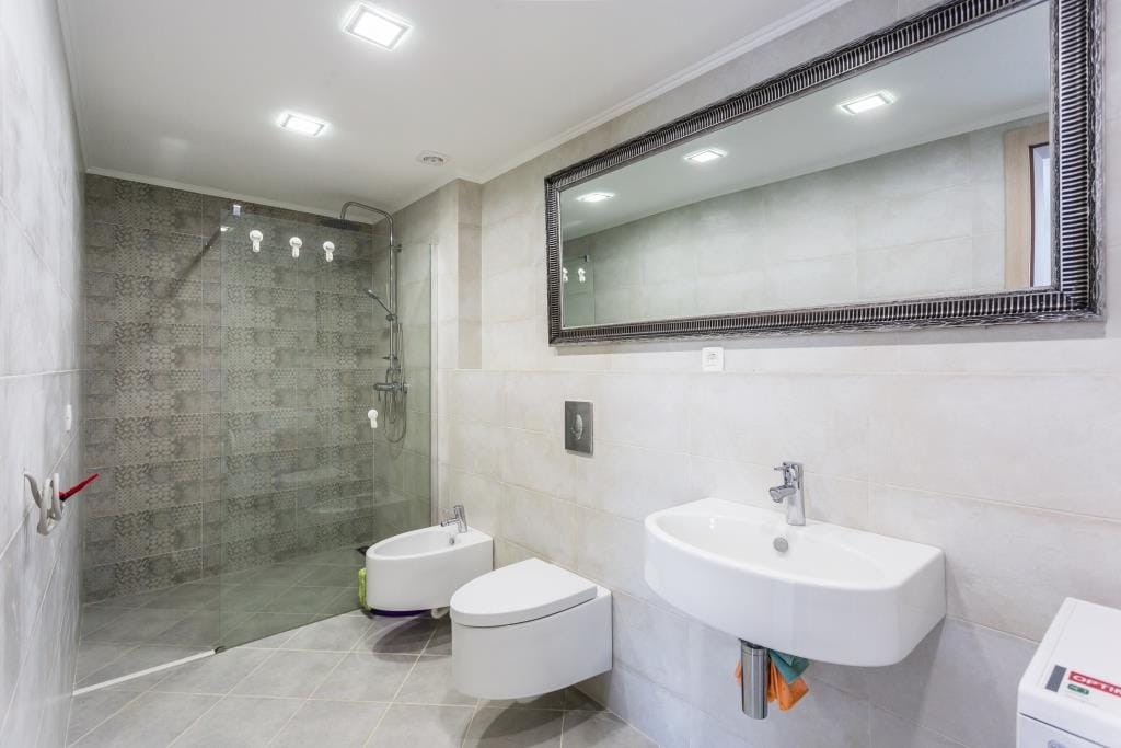 Modern bathroom with a shower cabin in a villa in Krašići, Montenegro: tiles, fixtures, and a large mirror.