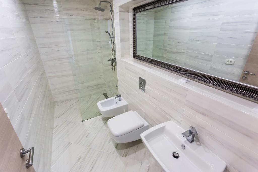 Modern bathroom with a shower cabin and bidet in a villa in Krašići, Montenegro: bright marble-look finishes.