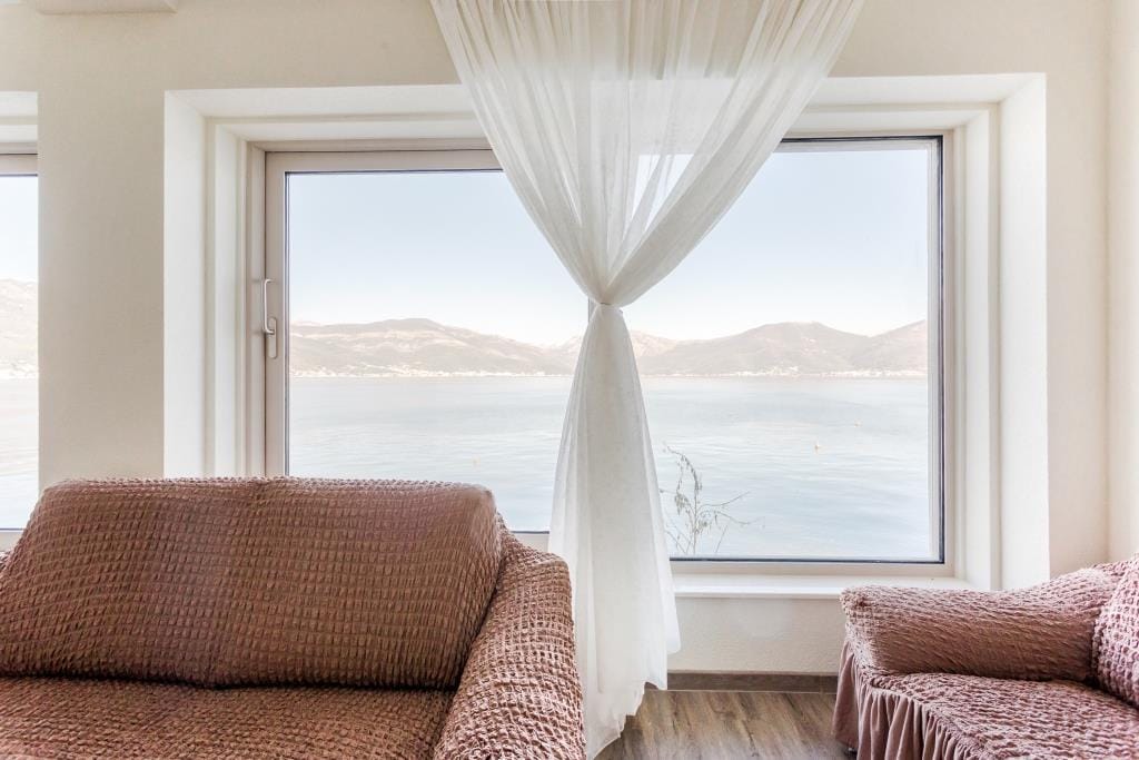 Living room with panoramic sea and mountain views in a villa in Krašići, Montenegro: soft furnishings and a bright interior.