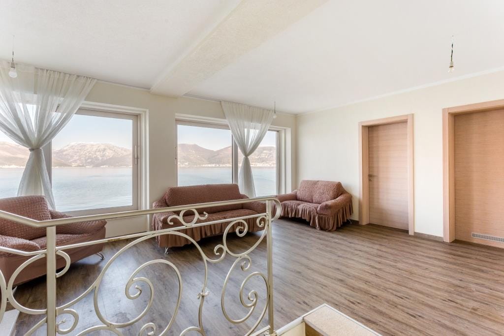 Living room with panoramic sea and mountain views in a villa, Krašići, Montenegro: soft seating and a bright interior.