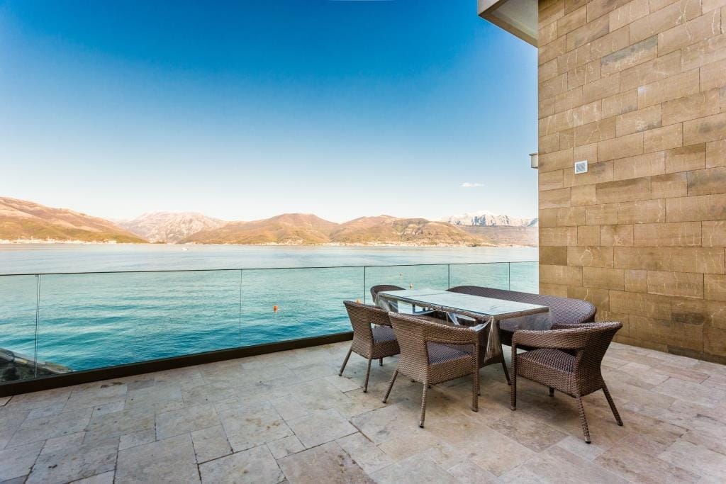 Villa terrace in Krašići, Montenegro: wicker furniture, stone finishes, and panoramic sea and mountain views.