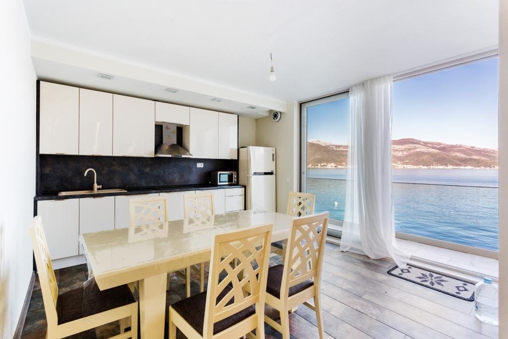 Modern kitchen in a villa in Krašići, Montenegro, with a dining area and panoramic sea and mountain views.