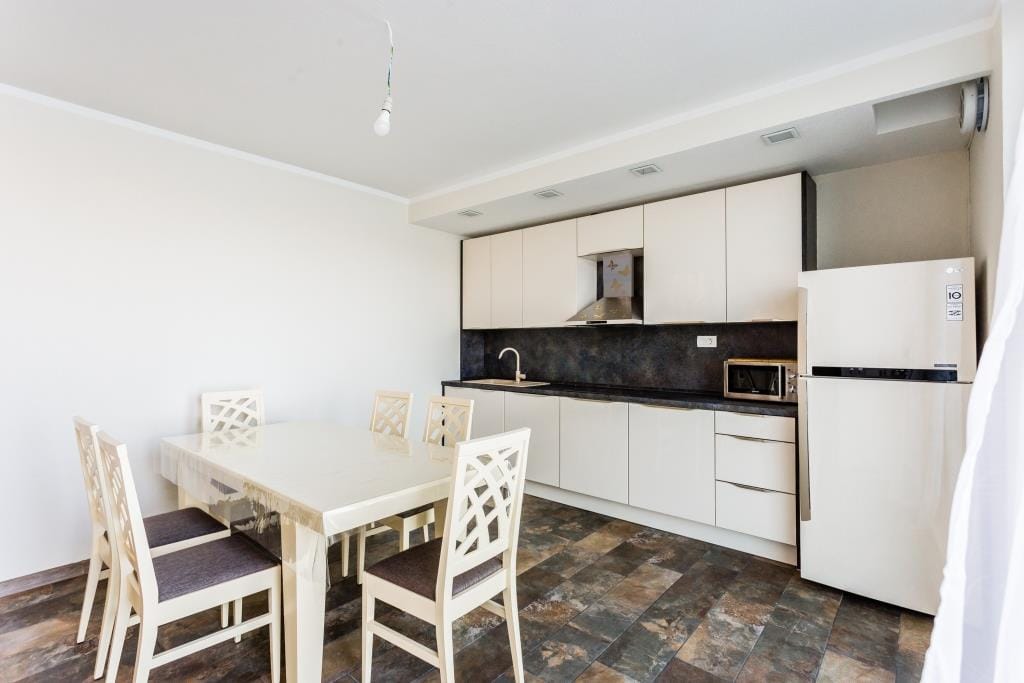 Modern kitchen with light cabinetry and a dining area in a villa in Krašići, Montenegro.