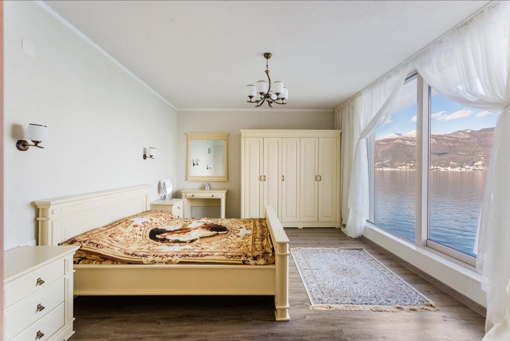 Bedroom with a double bed and panoramic sea and mountain views in a villa, Krašići, Montenegro.