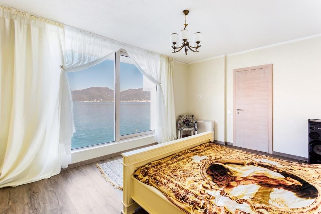 Bedroom in a villa in Krašići, Montenegro: double bed, panoramic windows with direct sea and mountain views.
