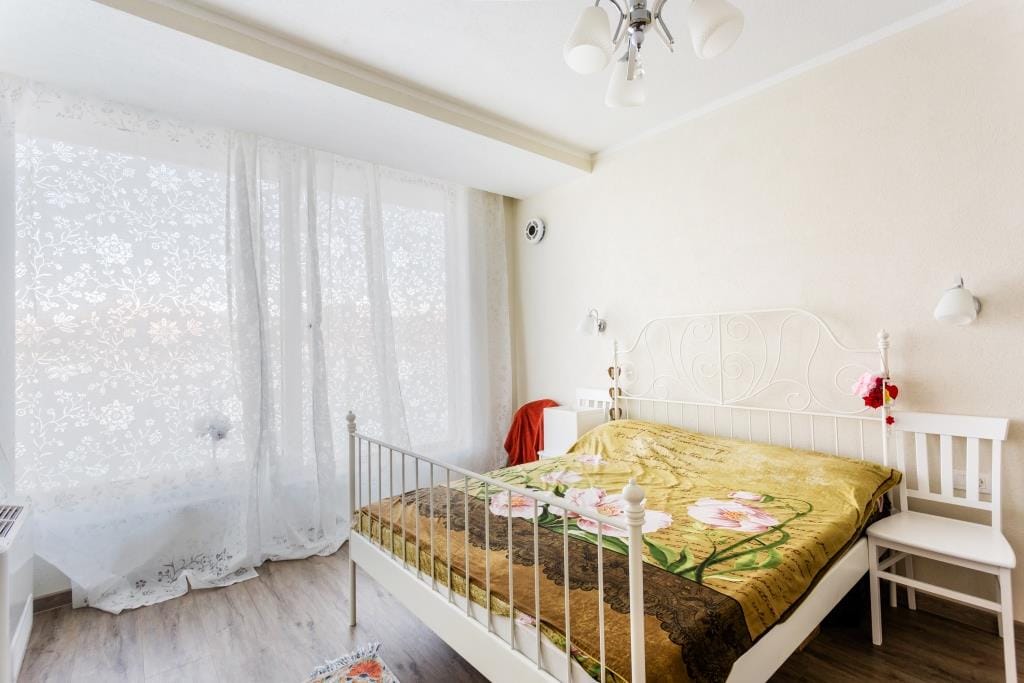 Bright bedroom with a white wrought-iron bed in a villa in Krašići, Montenegro: a cozy interior with a panoramic window.