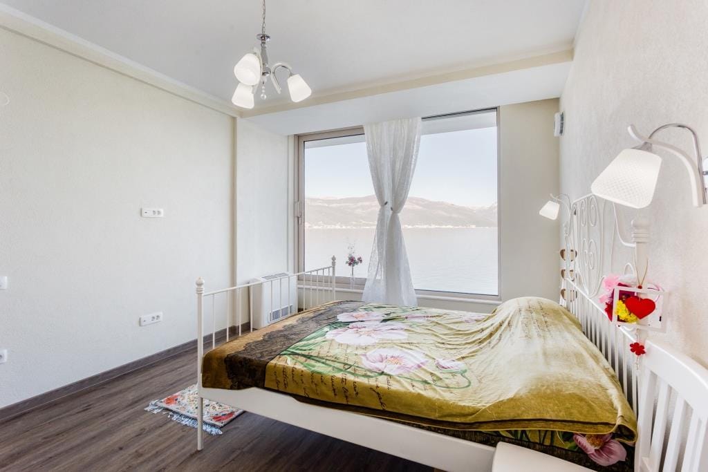 Bedroom with a double bed and panoramic sea view in a villa in Krašići, Montenegro.