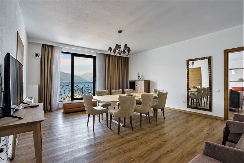 Living room with dining area and sea view in a villa in Krašići, Montenegro: modern furniture and panoramic windows.