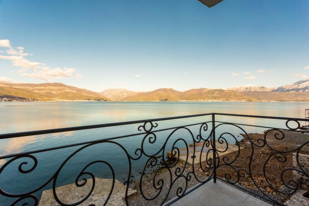 Sea and mountain view from the villa balcony in Krašići, Montenegro, with a wrought-iron railing and panoramic views of the coast.