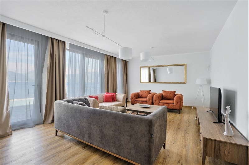 Modern living room with sea view in a villa in Krašići, Montenegro: soft seating, panoramic windows, and stylish decor.