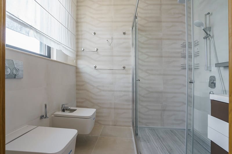 Modern bathroom with a shower cabin and bidet in a villa in Krašići, Montenegro: light tiles and fixtures.