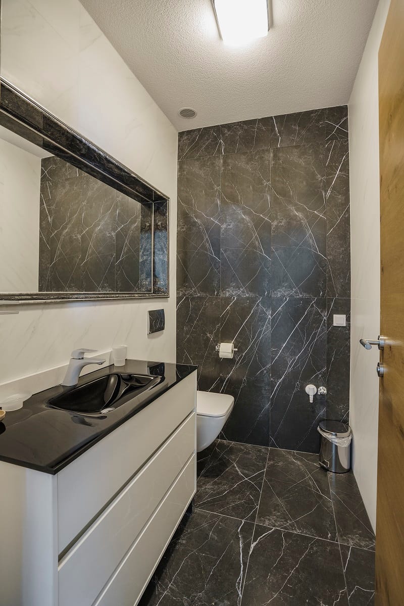 Modern bathroom with black marble finishes in a villa in Krašići, Montenegro: vanity and mirror.