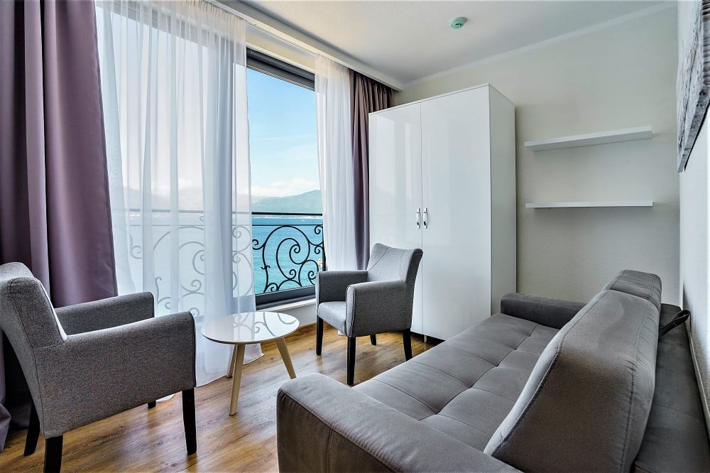 Living room with sea view in a villa in Krašići, Montenegro: soft seating, a white cabinet, and access to the balcony.