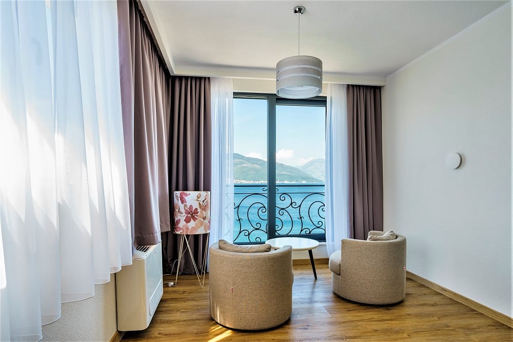 Living room with sea view in a villa in Krašići, Montenegro: two armchairs, a coffee table, and panoramic windows.