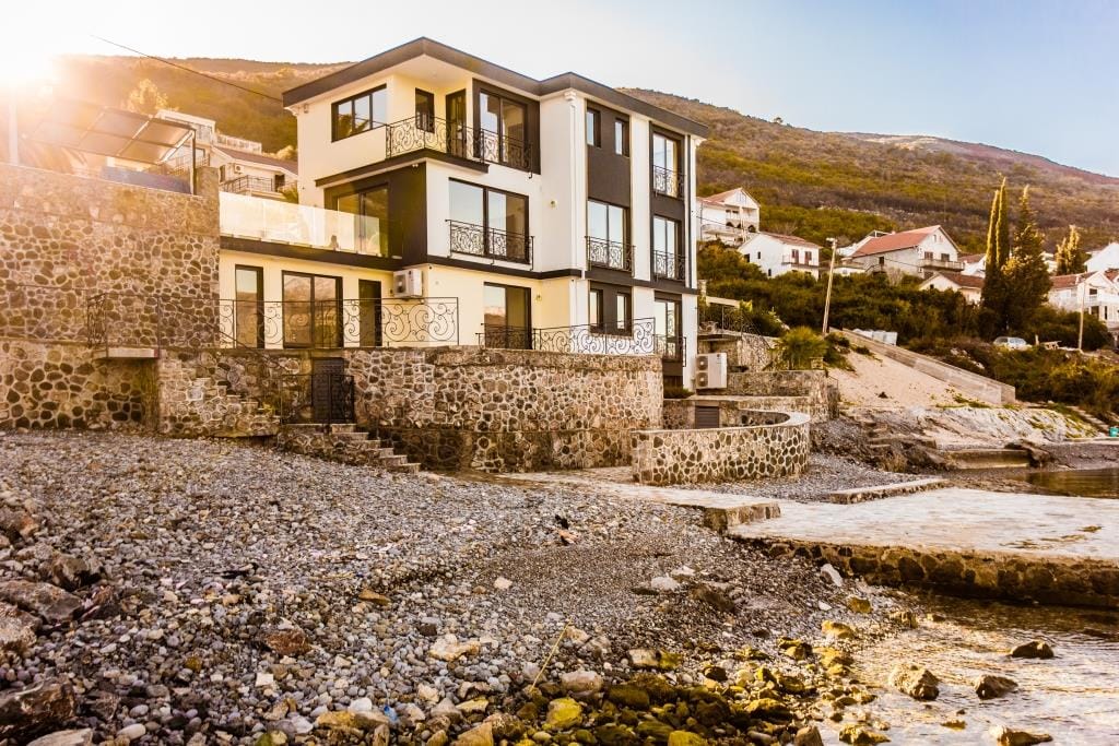 Modern villa on the seafront in Krašići, Montenegro: stone cladding, terraces, and panoramic windows.