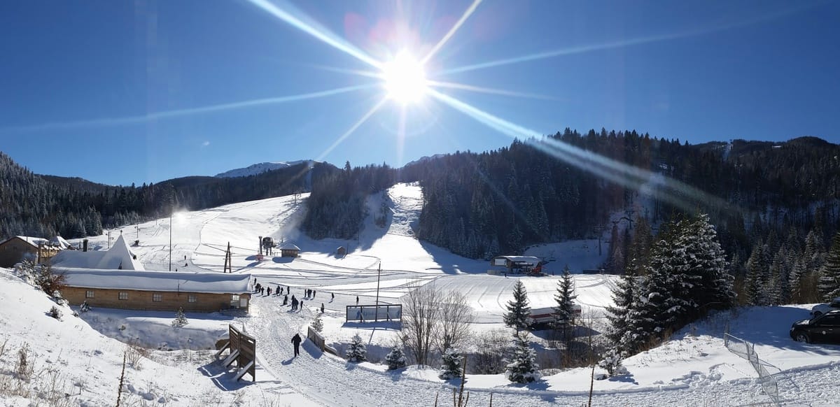 View of the ski resort and K1600 hotel in Kolašin, Montenegro: snow-covered slopes, ski lifts, and a sunny day.