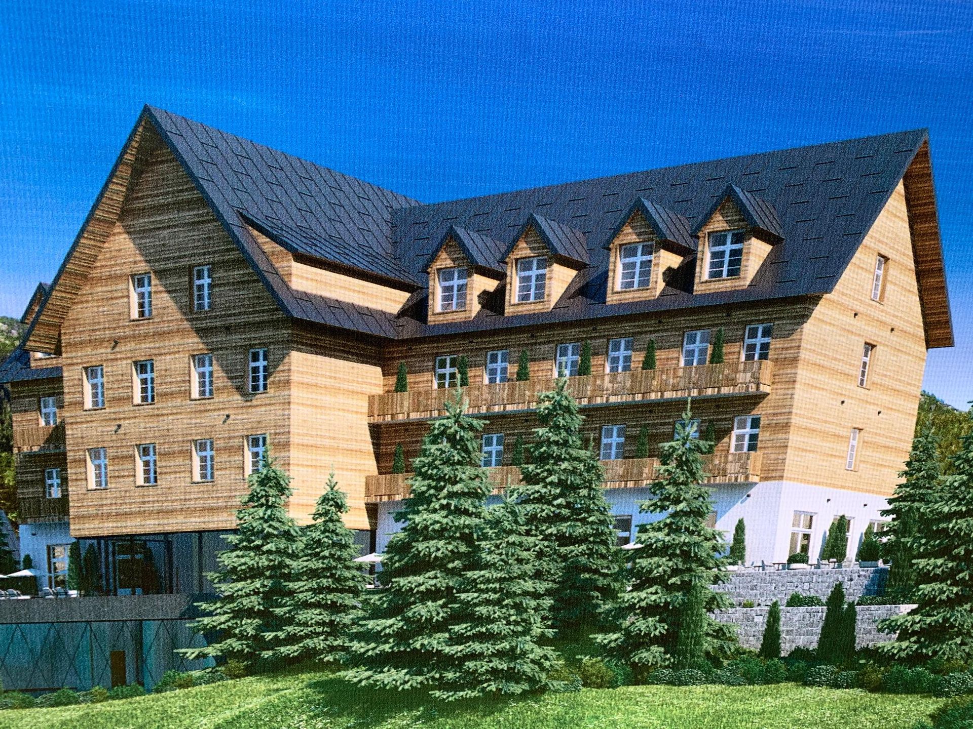 Facade of the Durmitor H&V hotel in Žabljak, Montenegro: a modern wooden building with balconies surrounded by fir trees.