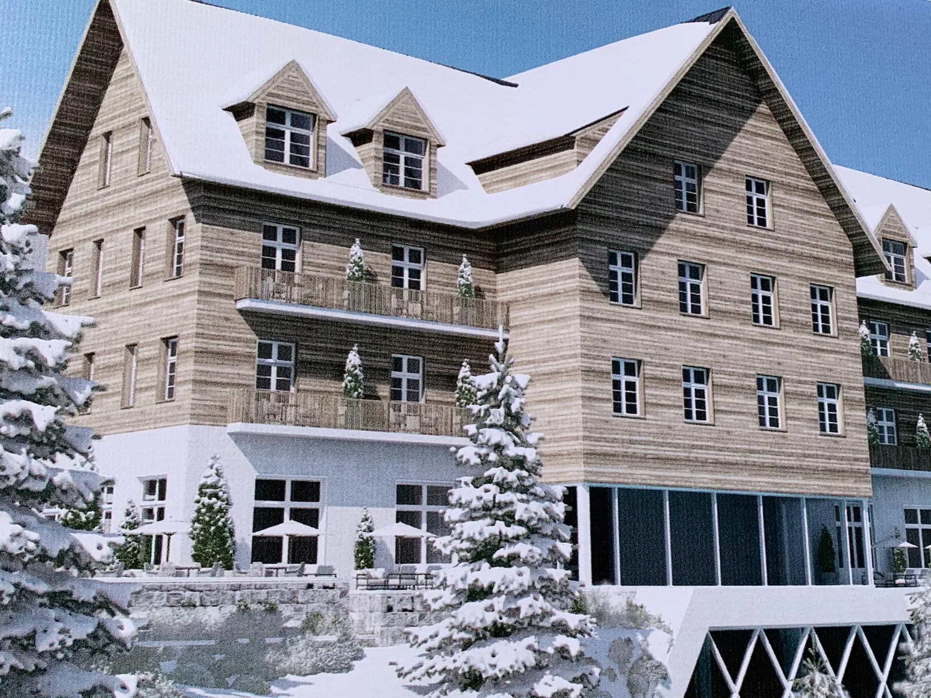Exterior of a multi-story wooden building in snow featuring balconies and pine trees.