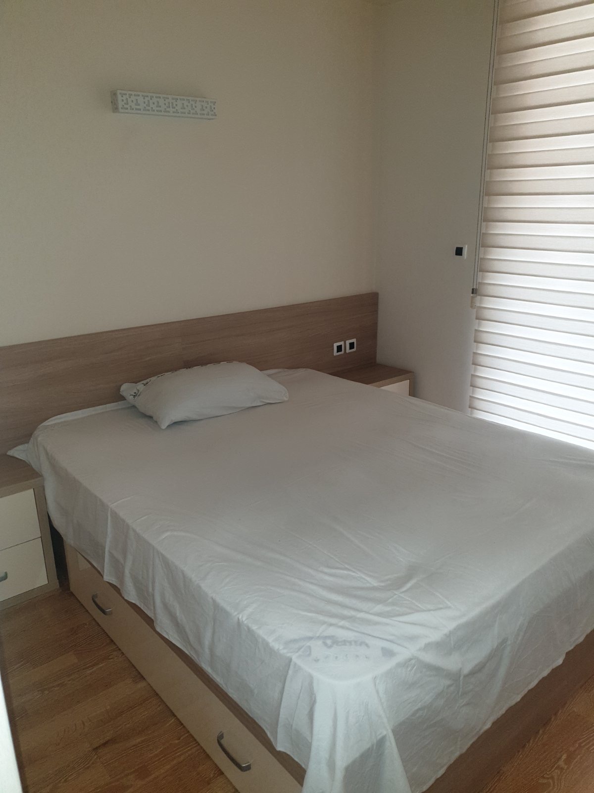 Bright bedroom with a double bed and wooden headboard in an apartment, Budva, Montenegro.