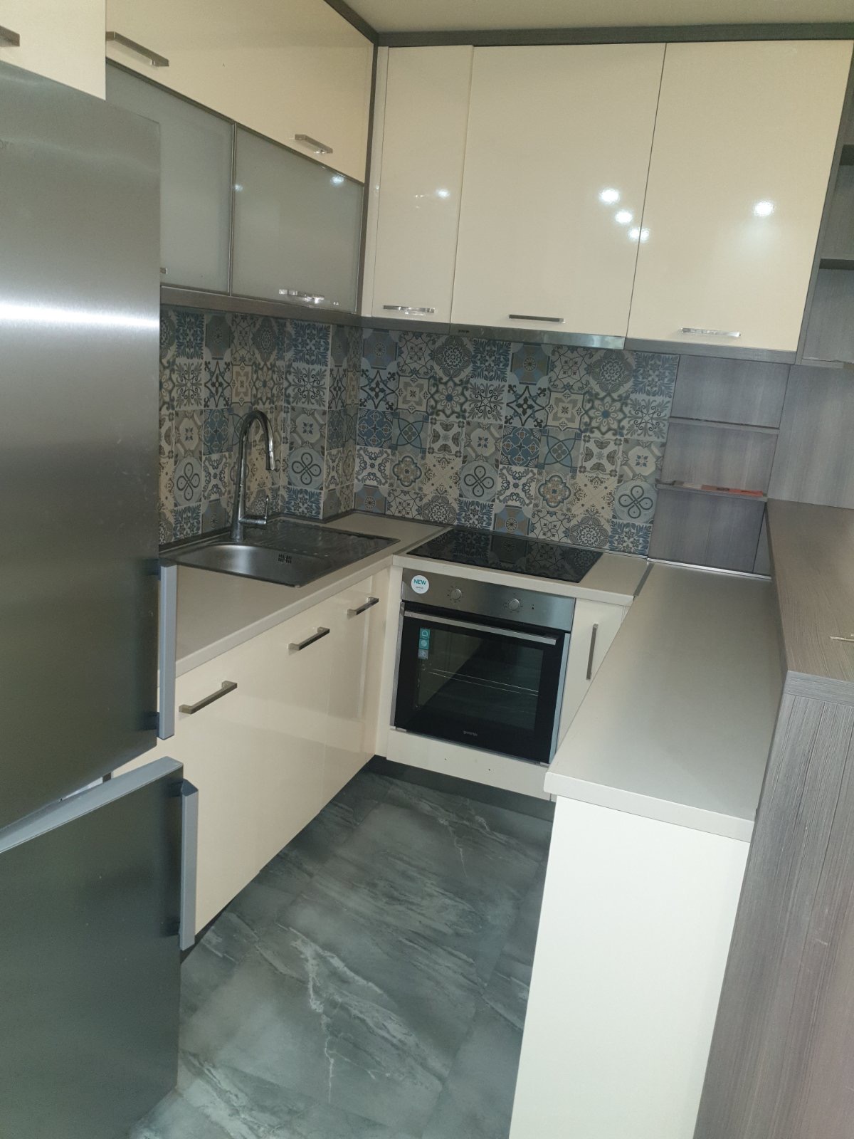 Modern kitchen in an apartment in Budva, Montenegro: light-colored cabinetry, patterned backsplash, and built-in appliances.