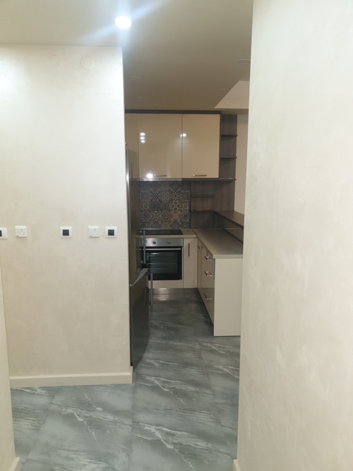 Modern kitchen in an apartment in Budva, Montenegro: light-colored cabinetry, built-in appliances, and patterned tile.