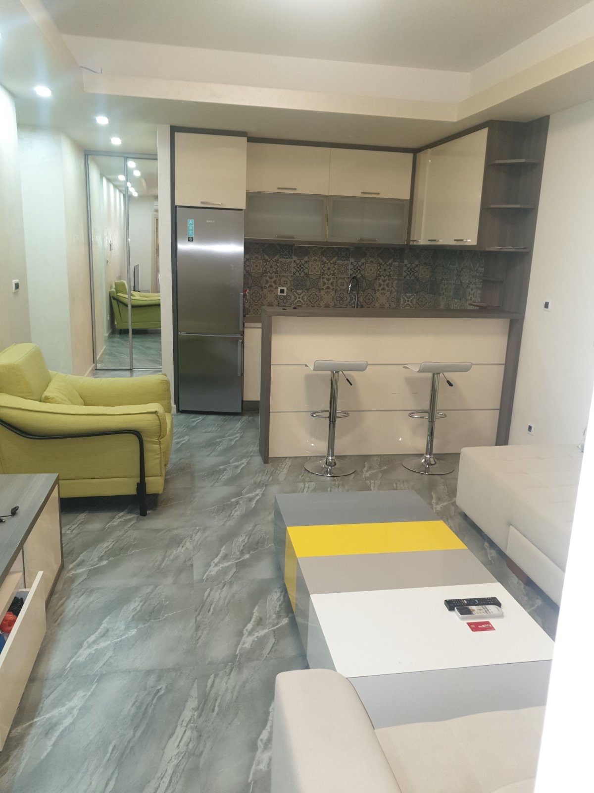 Modern living room with kitchen in an apartment in Budva, Montenegro: a bar counter, light furniture, and a stylish interior.