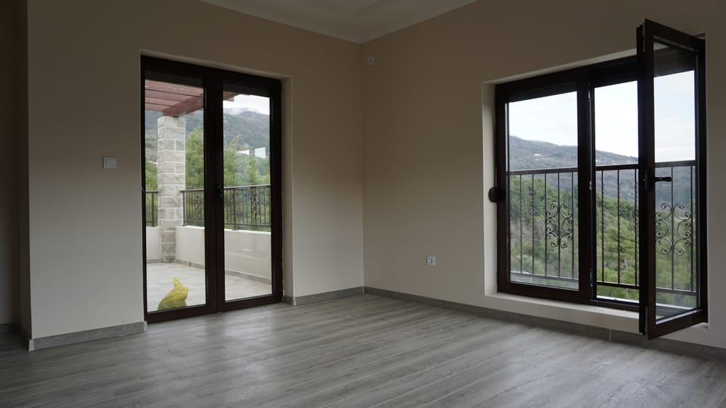 Bright living room in a villa in Igalo, Montenegro: panoramic windows, access to the terrace, mountain views, and modern finishes.