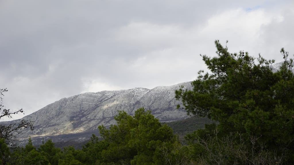 Picturesque view of snow-covered mountains and a coniferous forest from a villa in Igalo, Herceg Novi, Montenegro.