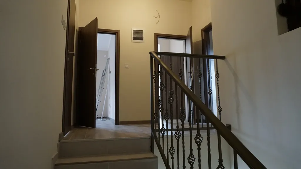 Interior staircase with ornate metal railing and open doors leading to adjacent rooms on the landing.