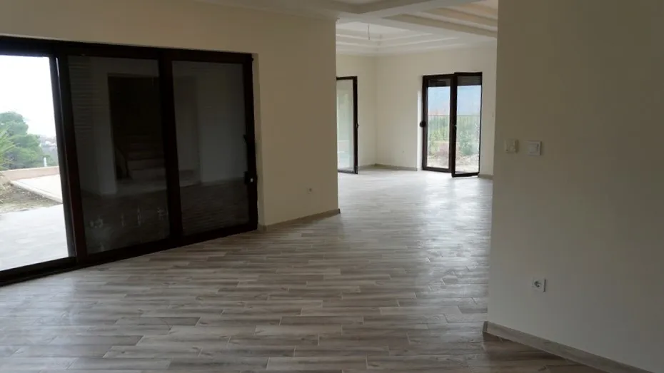 Empty room with wood-look flooring and large sliding glass doors leading outside.