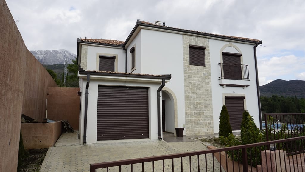 Two-story villa with a garage and stone facade in Igalo, Herceg Novi, Montenegro. View of the house and mountains.