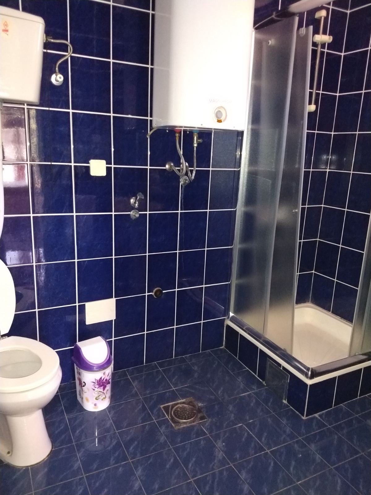 Bathroom with blue tiles, a shower cabin, and a boiler in a mini-hotel, Herceg Novi, Montenegro.