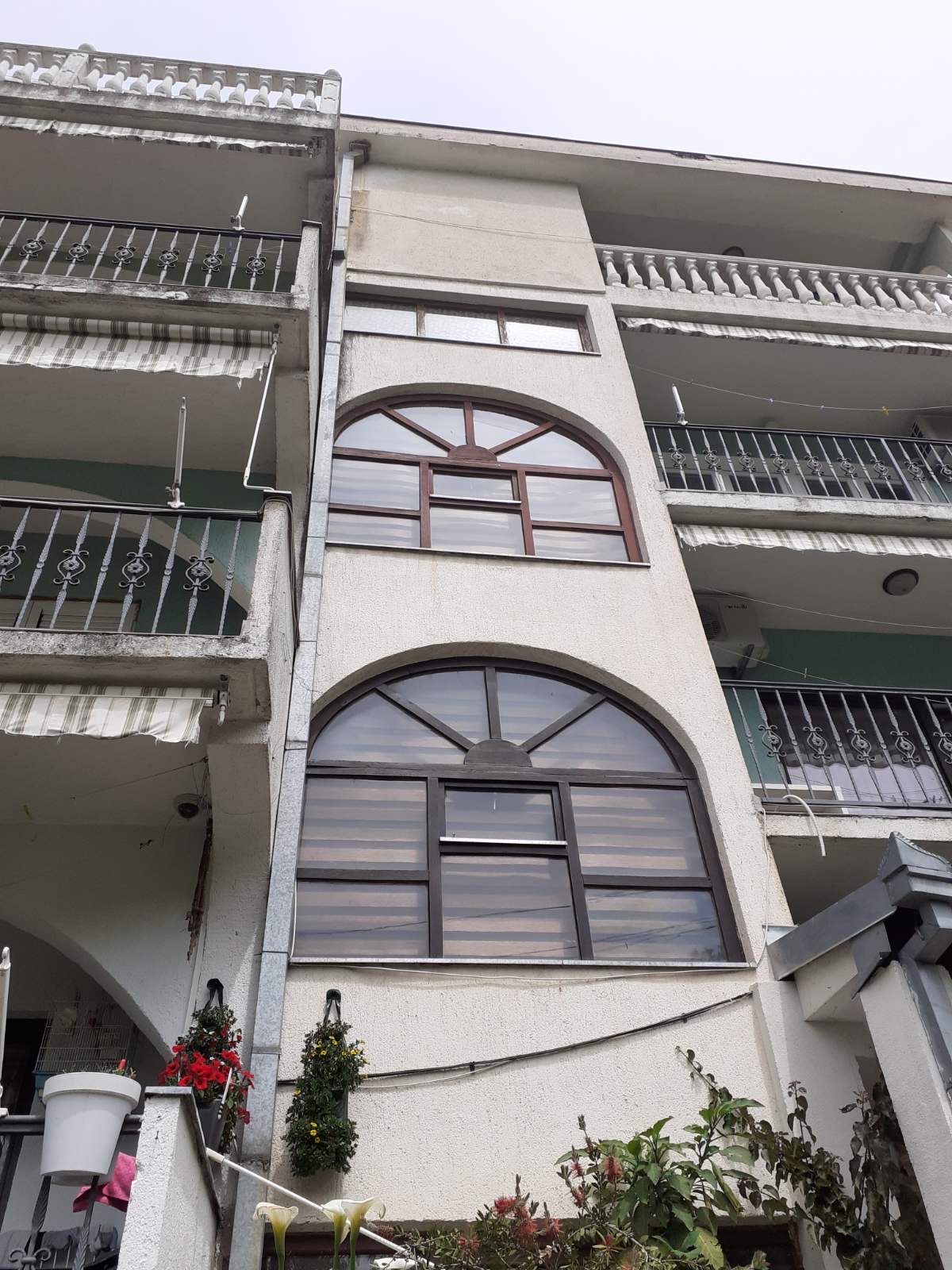 Facade of a mini-hotel in Zelenika, Herceg Novi, Montenegro: arched windows, balconies with wrought-iron railings, and floral decor.