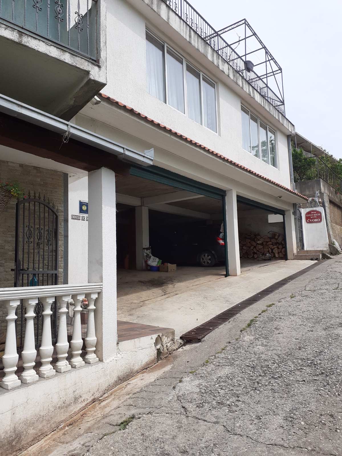 Facade of a mini-hotel in Zelenika, Herceg Novi, Montenegro: covered parking, a terrace with balustrade, and the guest house entrance.