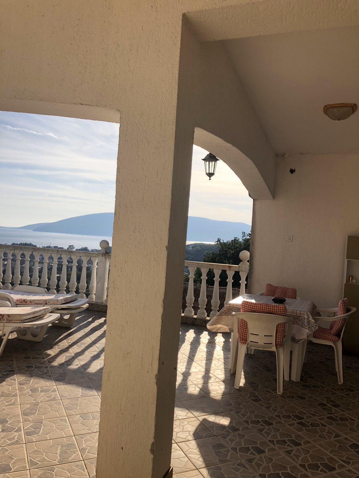 Terrace with sea view at the Zelenika mini-hotel, Herceg Novi, Montenegro: table, chairs, and sun loungers on the balcony.