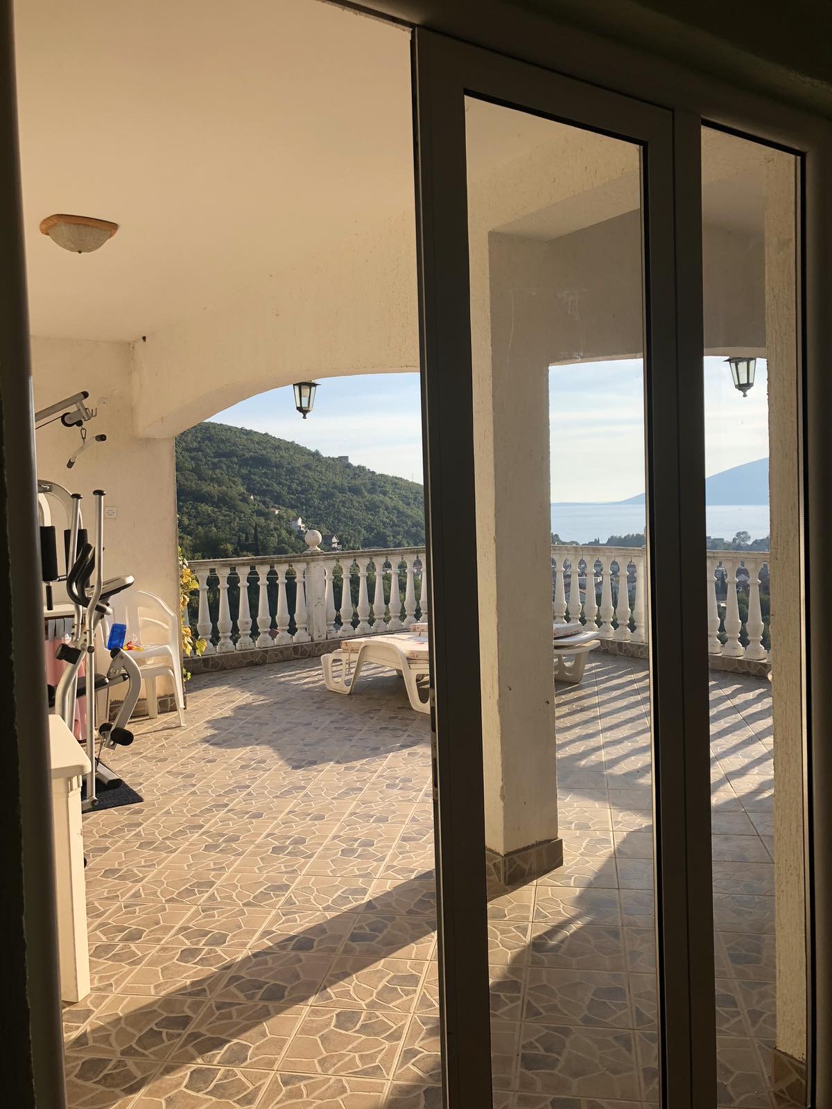 Spacious terrace with sea and mountain views at the Zelenika Hotel, Herceg Novi, Montenegro: tile flooring, sun loungers, and exercise equipment.