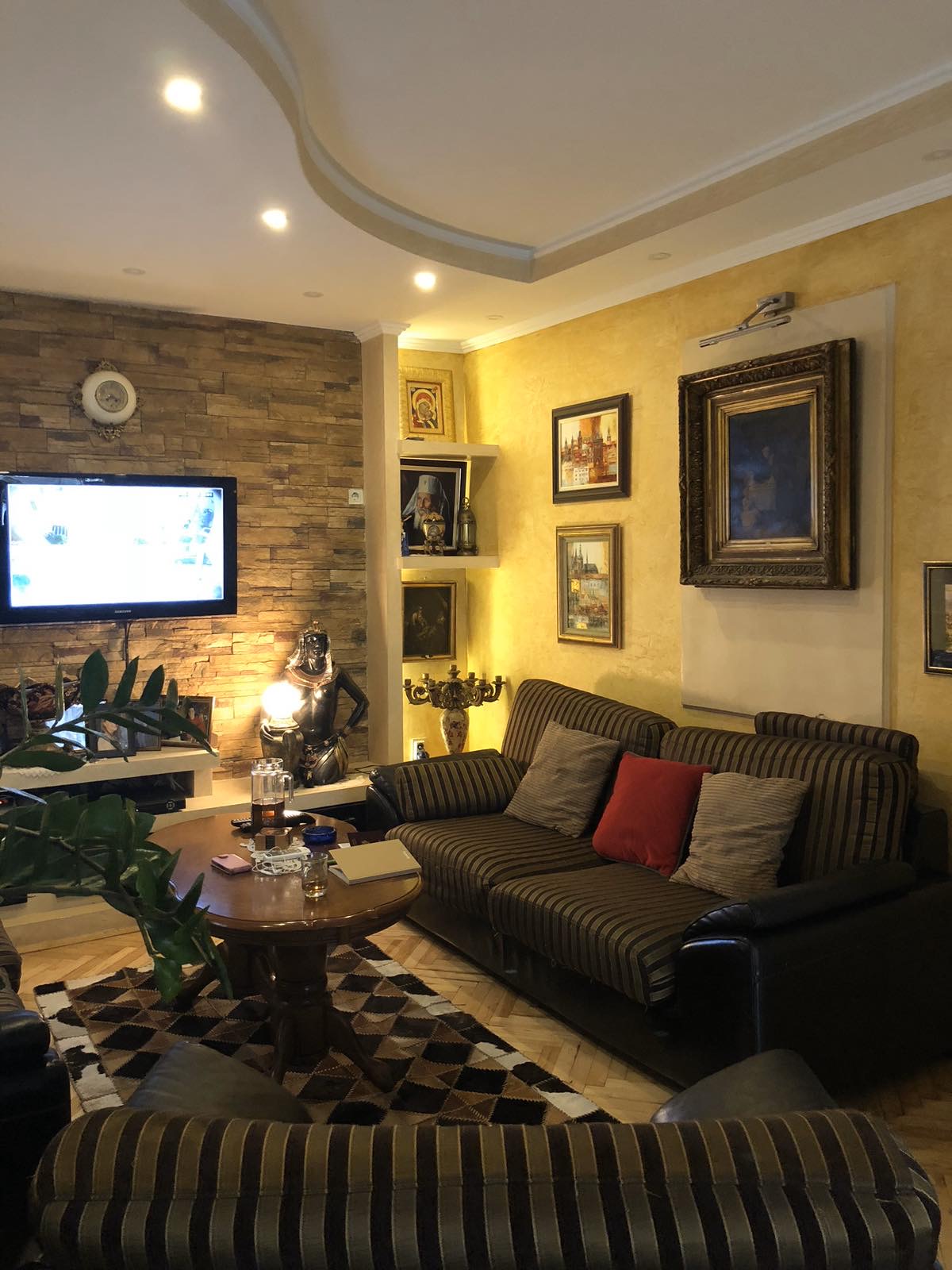 Cozy living room in a mini-hotel in Zelenika, Herceg Novi, Montenegro: striped sofa, stone decor, and paintings on the walls.