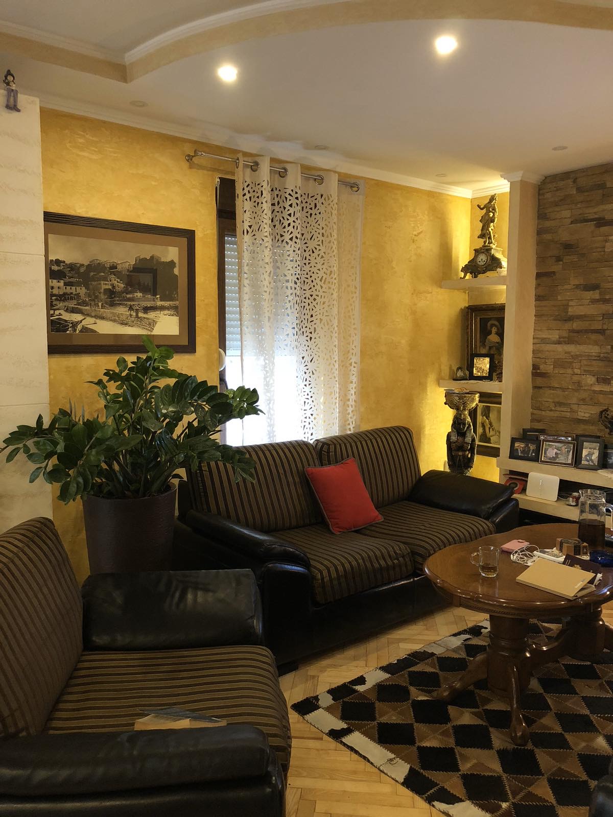Living room in the Zelenika mini-hotel, Herceg Novi, Montenegro: yellow walls, striped sofas, a fireplace, and decorative interior details.